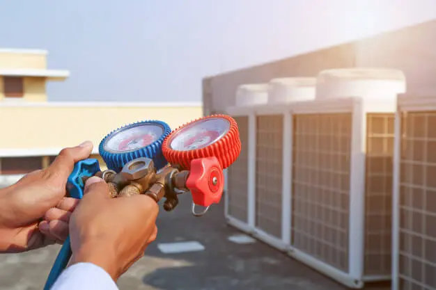 technik-stosujacy-urzadzenia-pomiarowe-do-napelniania-fabrycznych-klimatyzatorow-przemyslowych_101448-1274-1